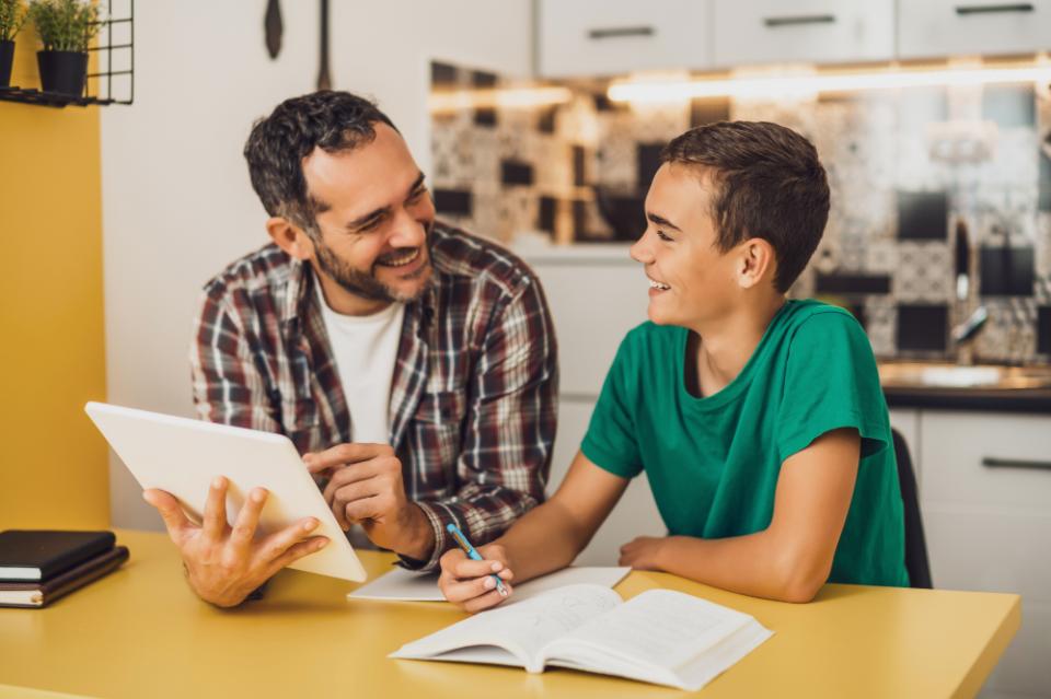 Father is helping his son with learning. They are doing homework together.