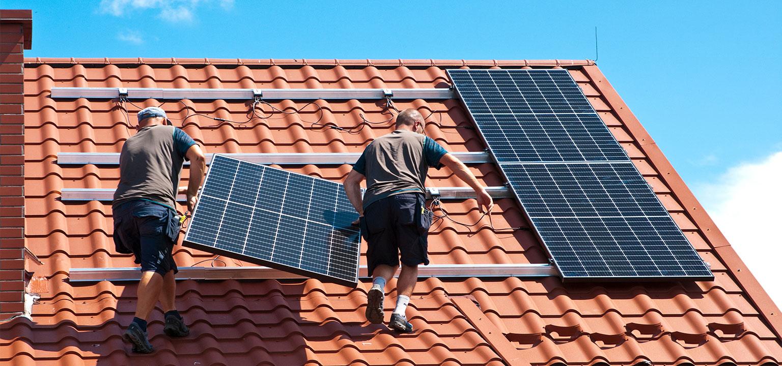 Installateurs plaatsen zonnepanelen op een rood dak