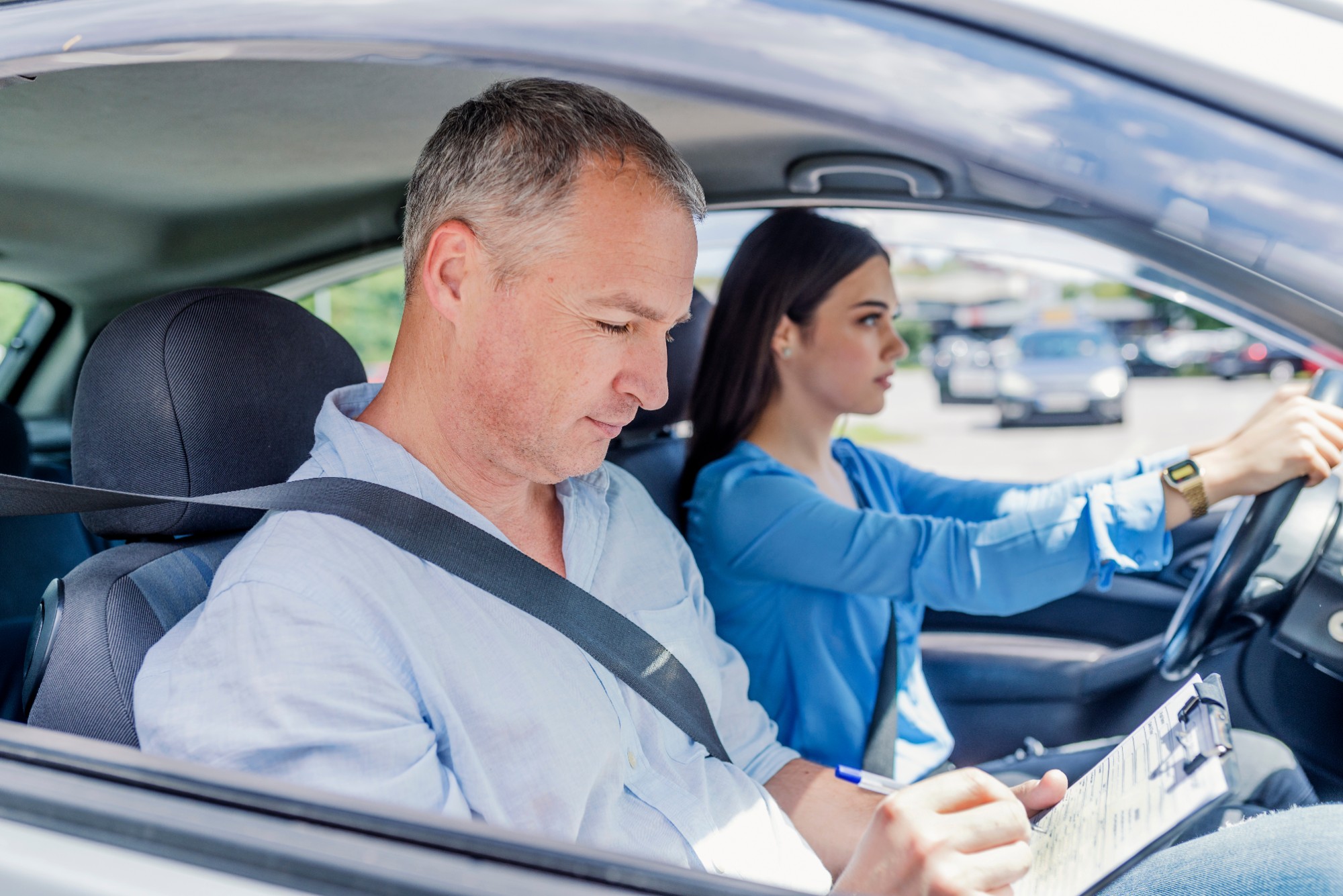 Instructor of driving school giving exam while sitting in car.