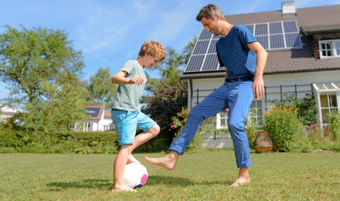 Un père et son fils jouent au foot devant la maison équipée de panneaux solaires sur le toit. Sont-ils assurés?